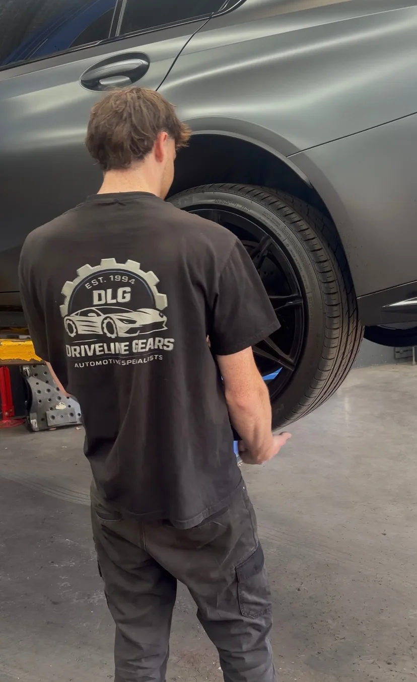 Driveline Gears mechanic working on the front wheel of a grey car in the workshop
